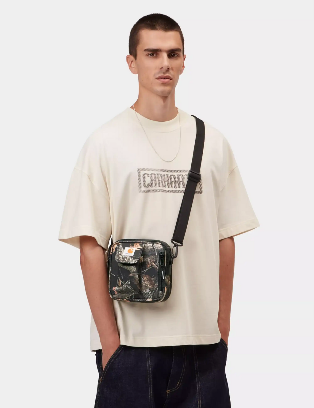 Small camo crossbody bag with front zipper pocket and shoulder strap, dark tones