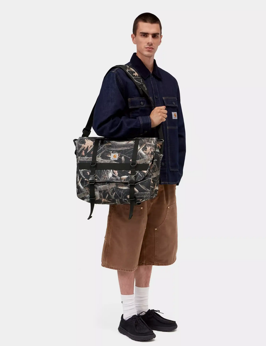 Black camo messenger bag with two front buckled straps and shoulder strap.