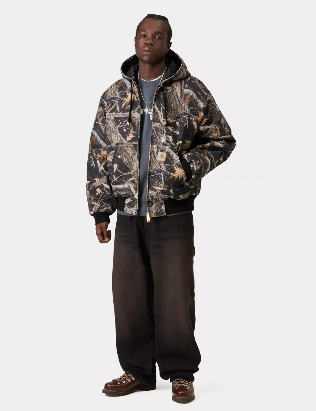 Carhartt WIP OG Active jacket in black feather-tree camouflage, hood with dark lining.