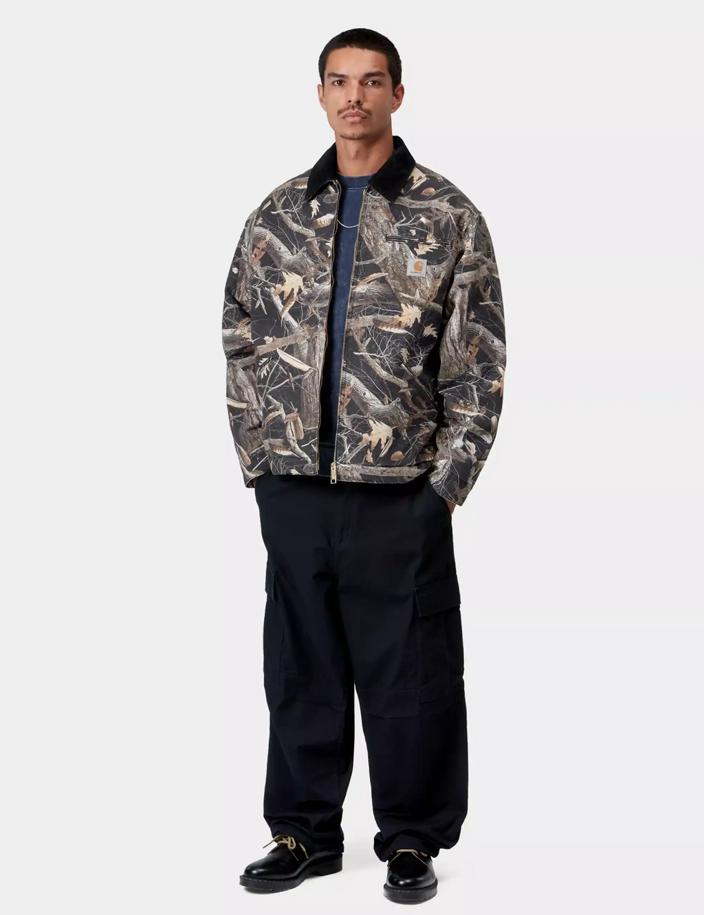Men's camo feather-pattern work jacket with black stand collar, paired with dark pants.