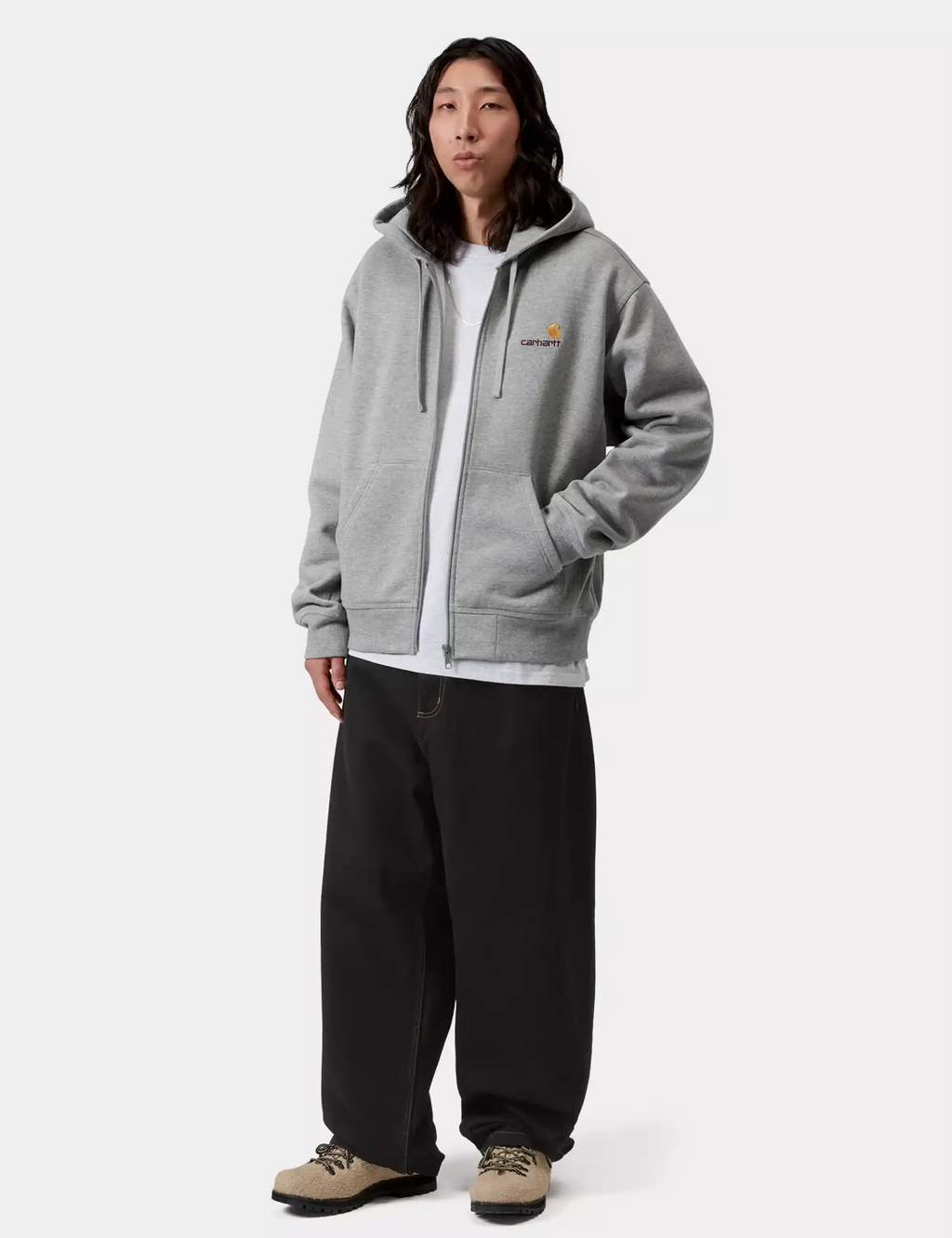 Model wearing black denim pants with relaxed wide legs and a casual hoodie