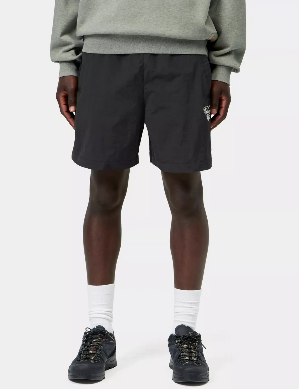 Black shorts with elastic waistband and logo patch, worn with crew socks and shoes
