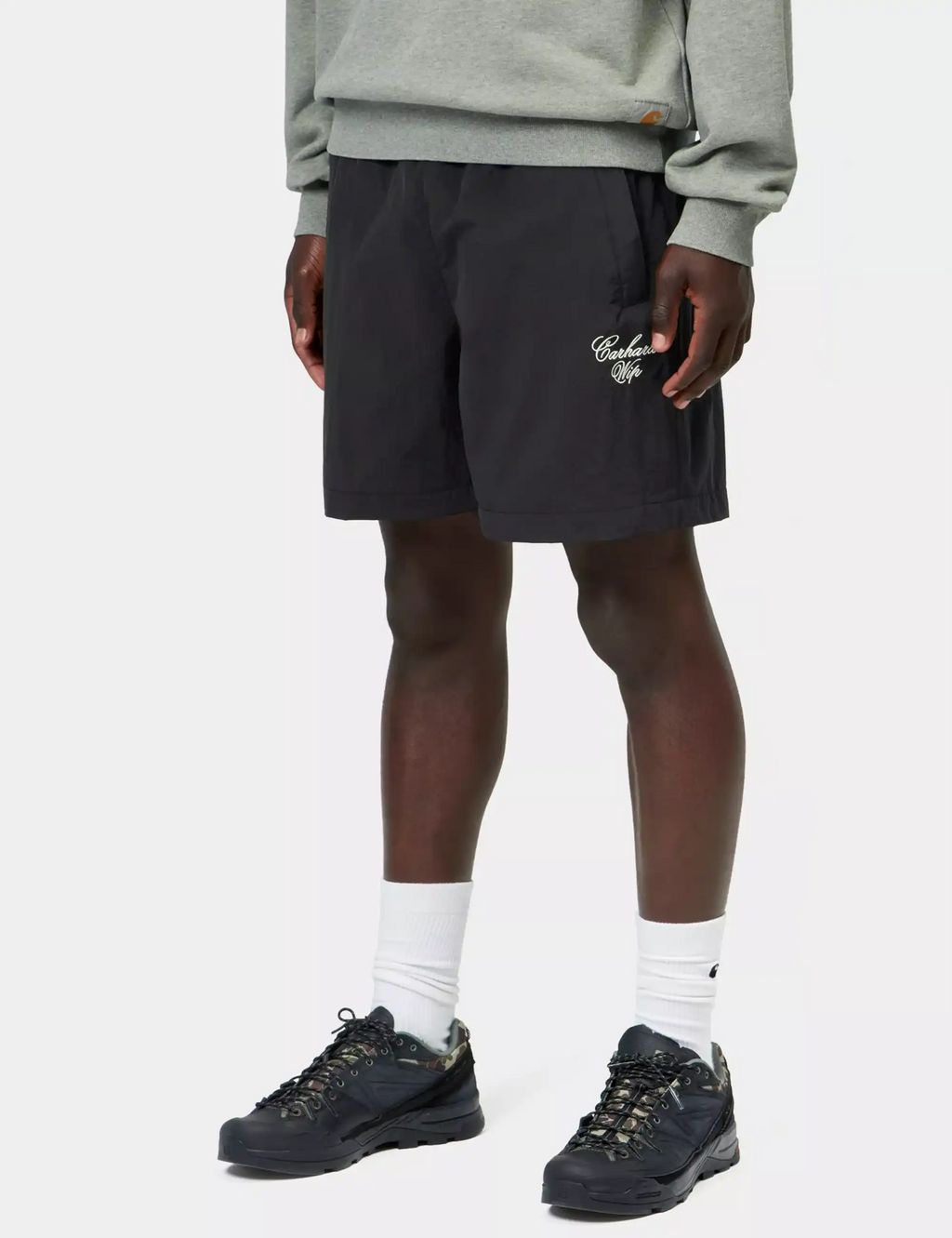 Black shorts with elastic waistband and back logo embroidery, worn with sneakers
