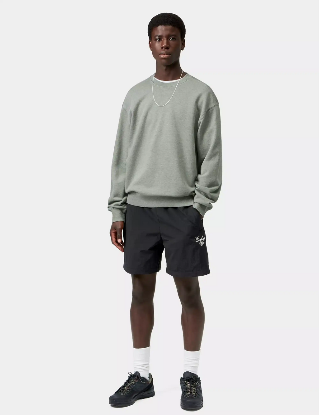 Black shorts with elastic waistband and logo, styled with sweatshirt, socks, and sneakers