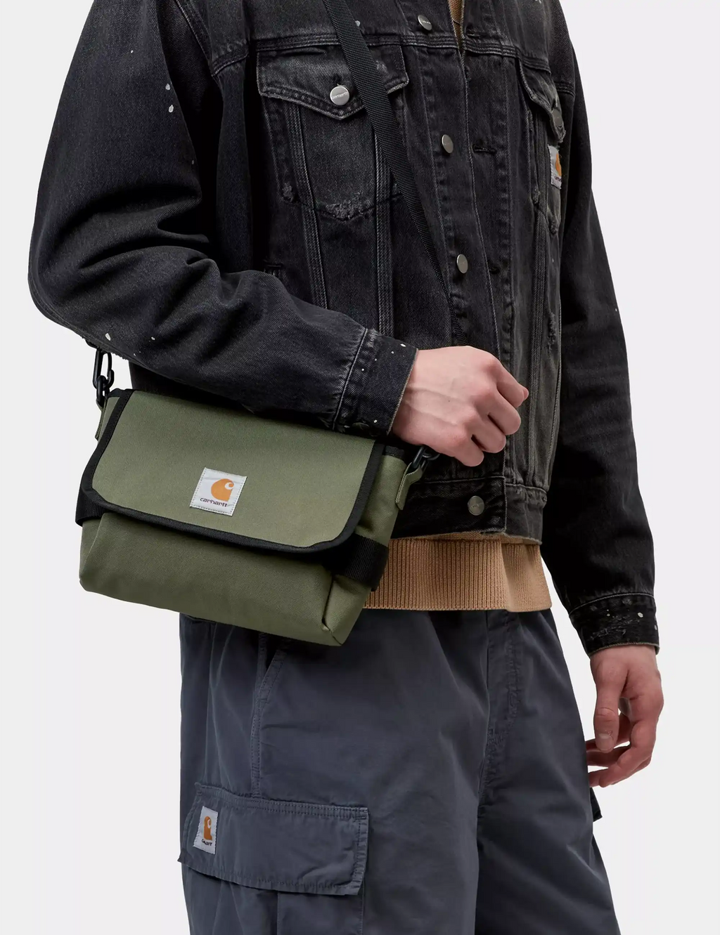 Olive green crossbody shoulder bag with flap and logo patch, worn on model