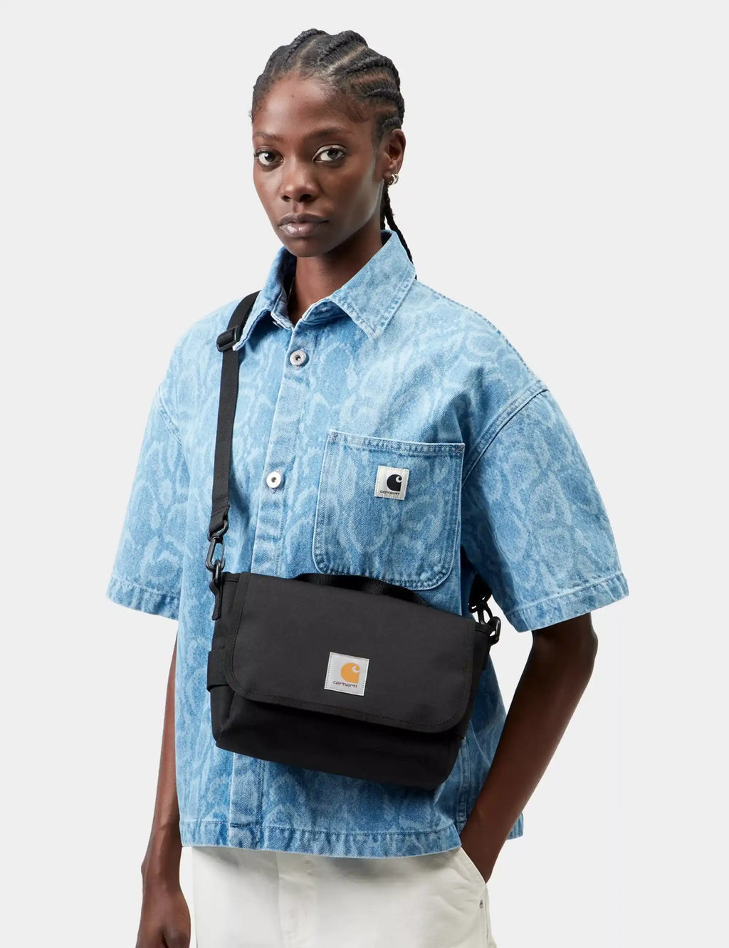 Black shoulder bag with flap, front logo patch, and adjustable strap