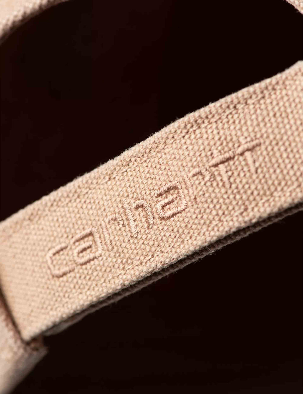Canvas cap fabric tag with embroidered text on brown canvas