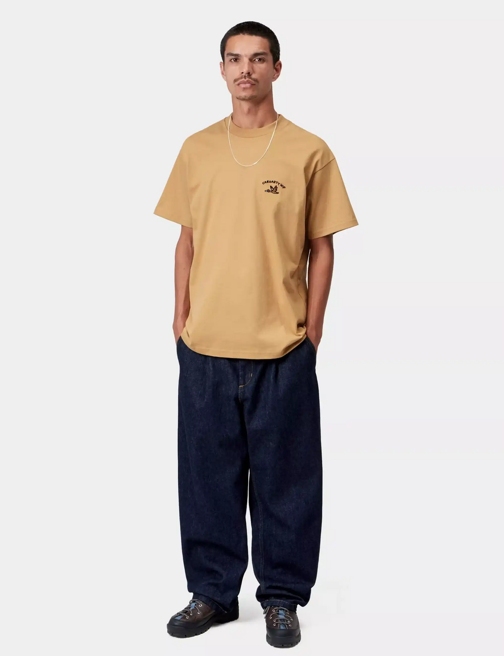 Tan crew-neck T-shirt with chest duck logo, model full-body front view