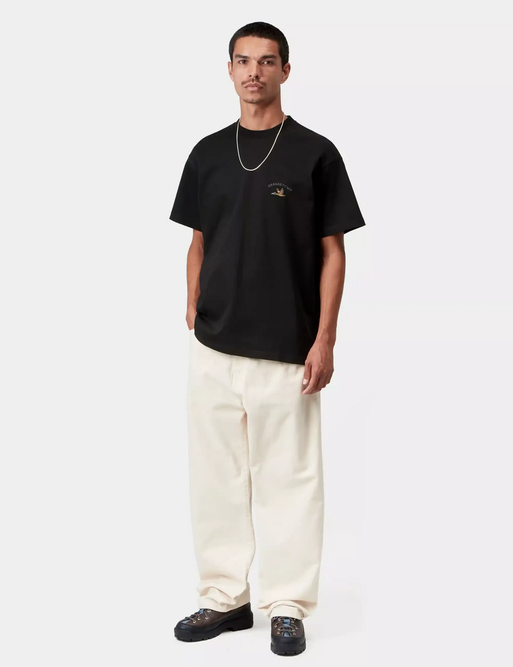 Black Carhartt WIP T-shirt with duck chest graphic, styled with light pants