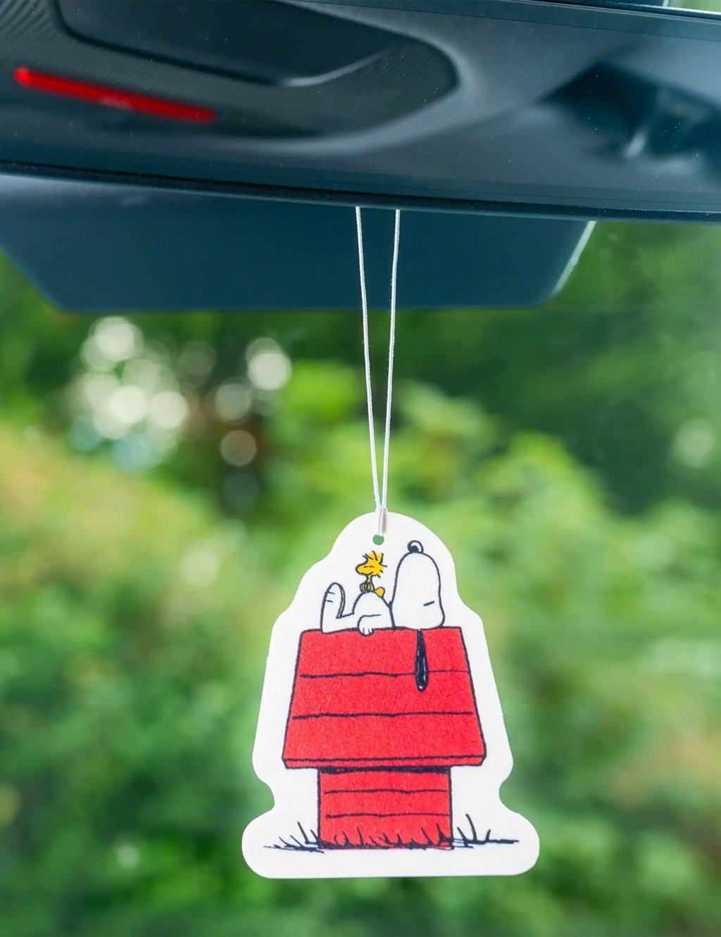 Snoopy air freshener tag hanging from a vent, white card with red outfit