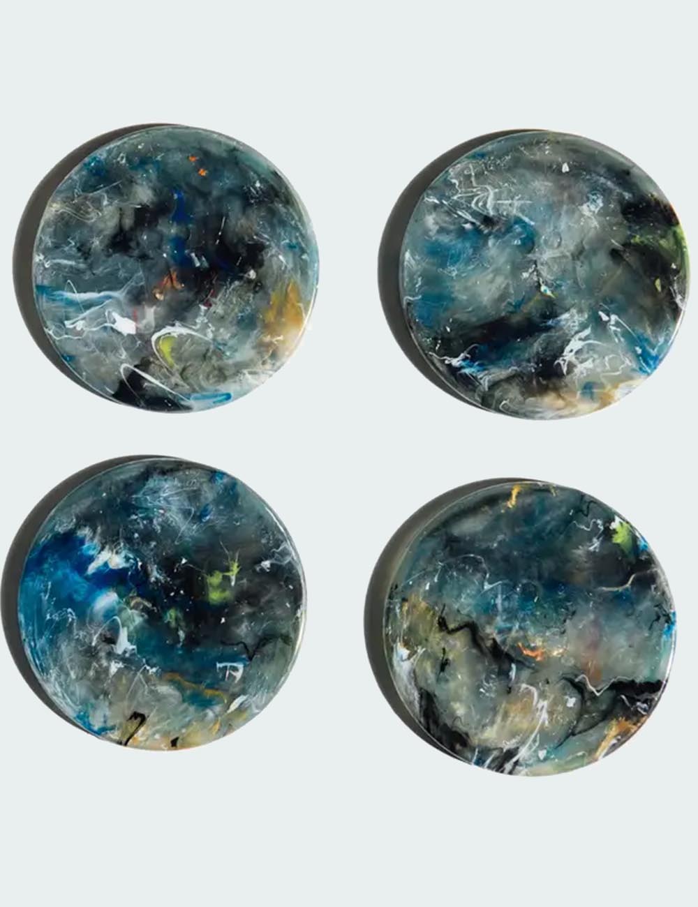 Four round, marbled blue and black objects on a light gray background