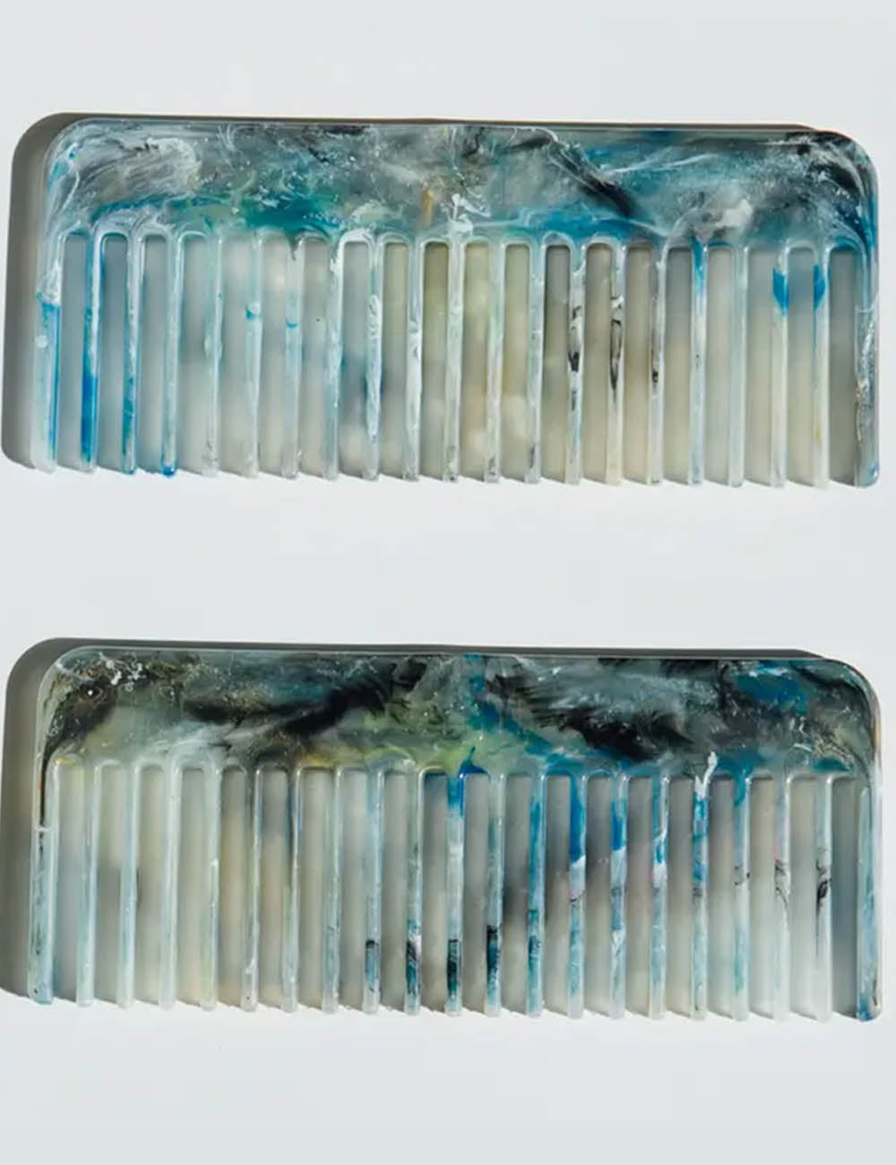 Two decorative combs with a blue and white abstract design on a light gray background