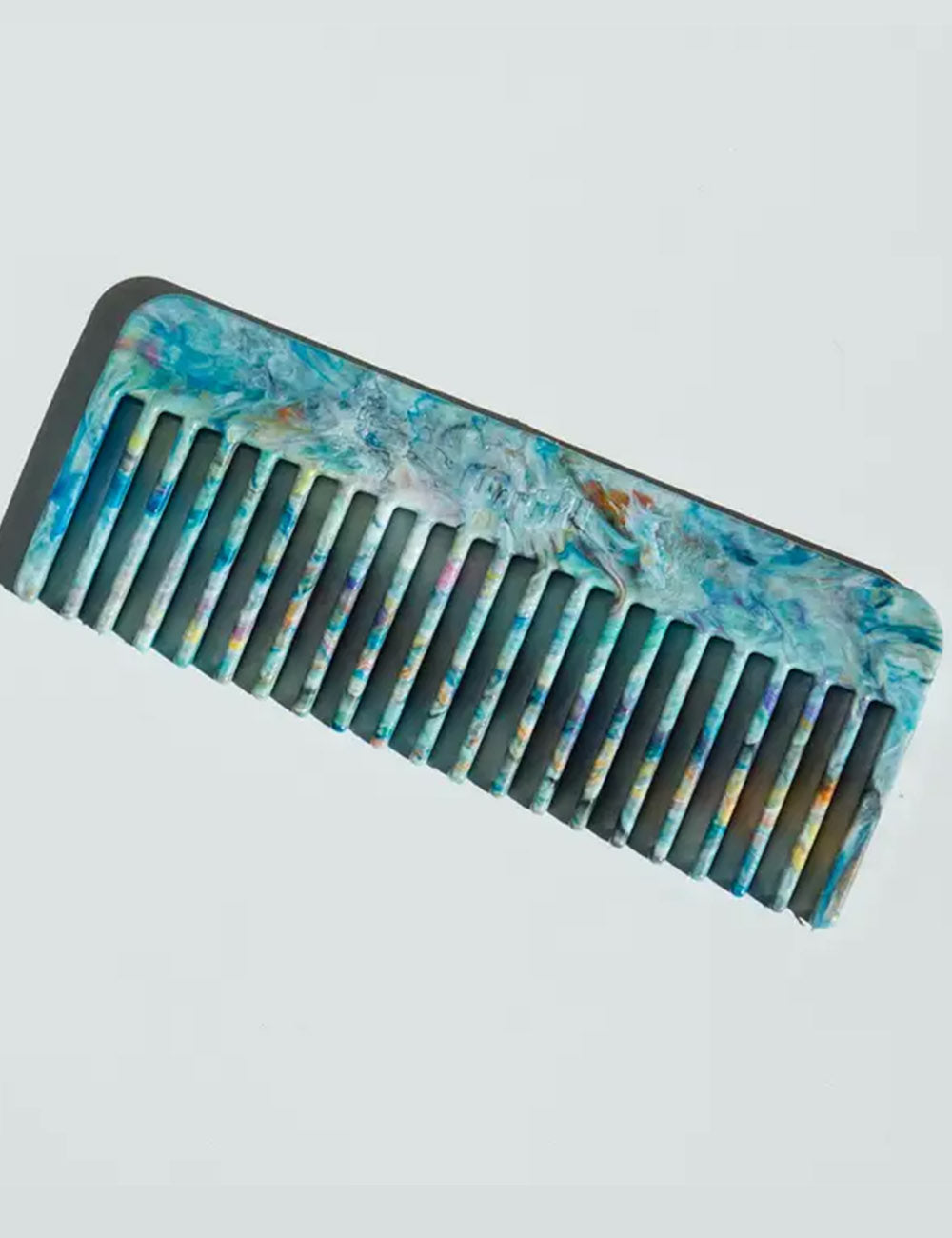 Decorative comb with a multicolored handle on a light gray background