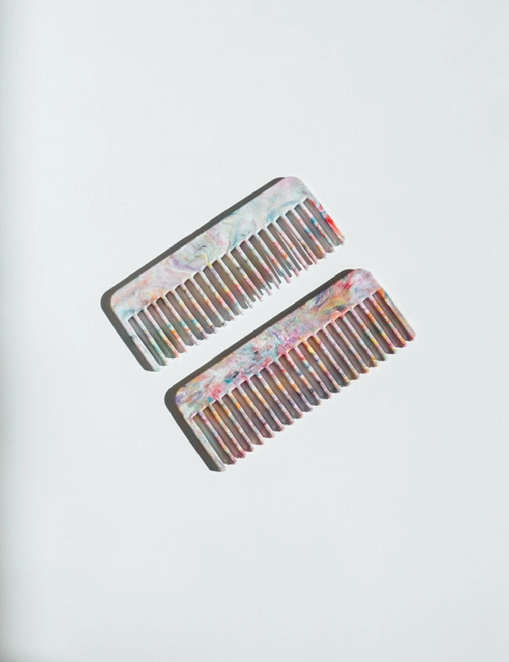Two decorative combs with floral patterns on a light gray background