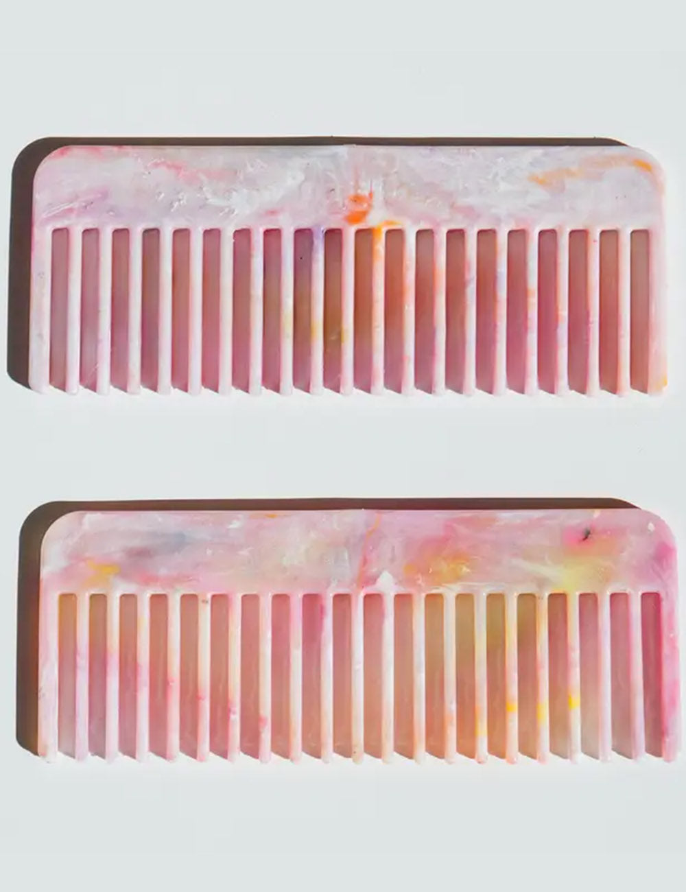 Two pink and orange tie-dye combs on a white background