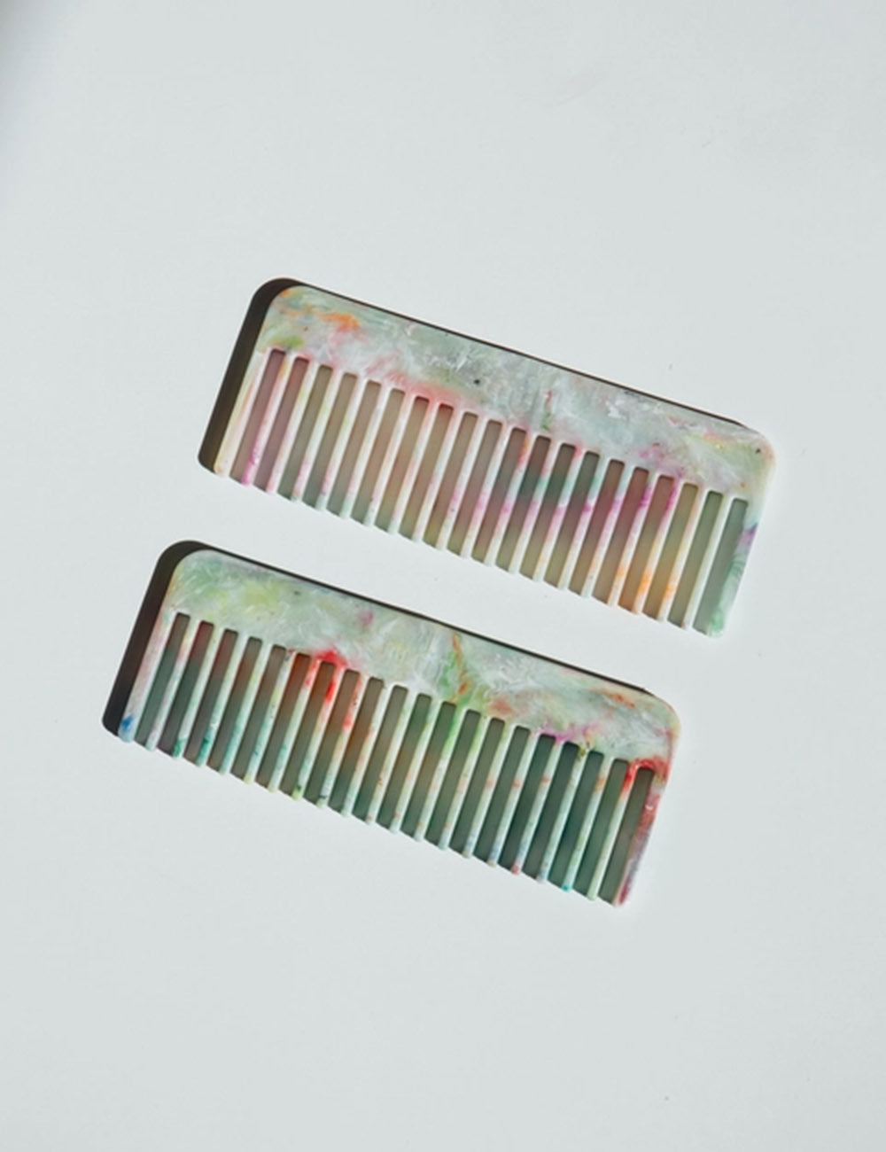 Two marbled combs on a light gray background