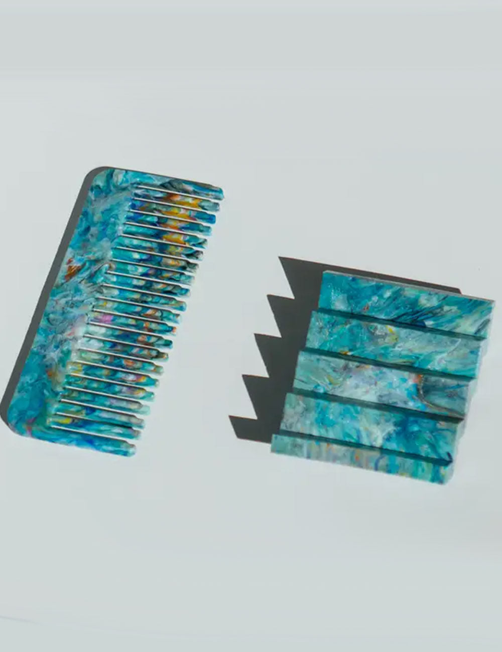 Blue and green marbled hair comb and clip on a light gray background