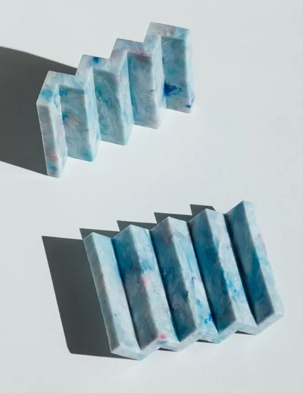 Blue and pink marbled soap bars on a light gray background
