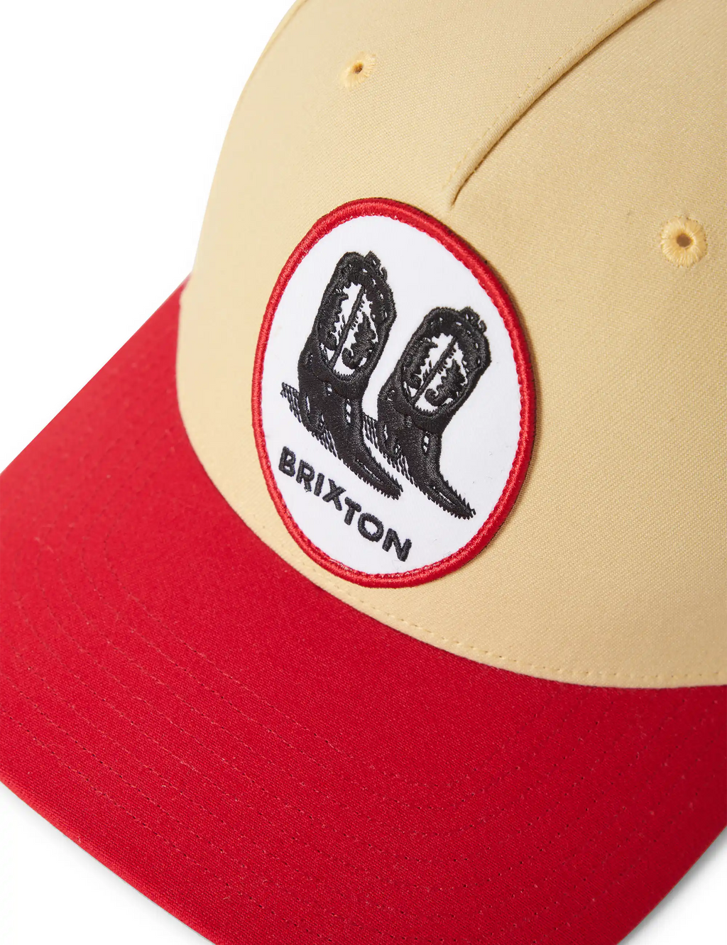 Cream snapback cap with red brim and circular Brixton hand logo patch