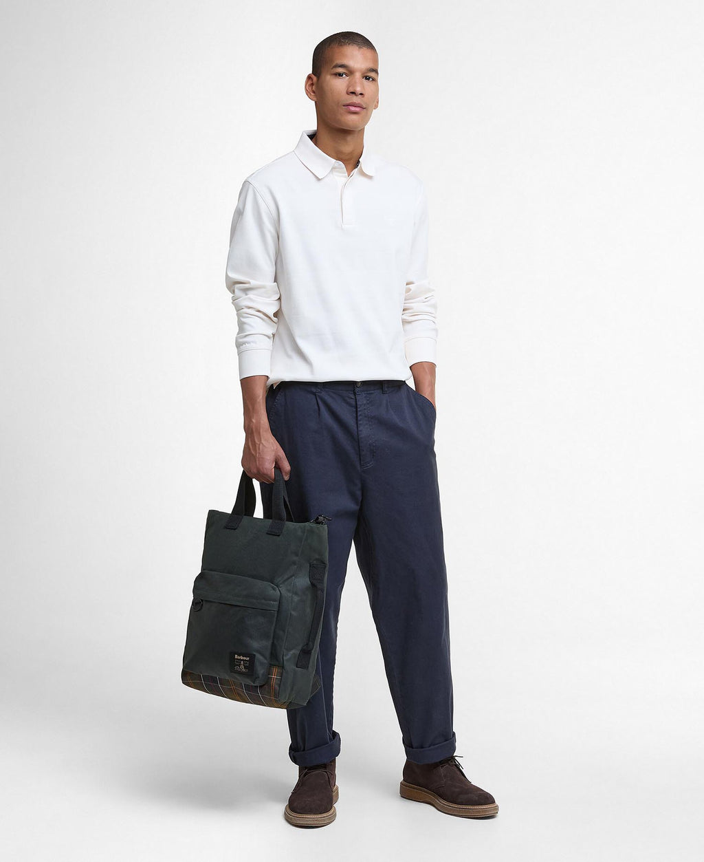 Dark green backpack with front pocket and tartan base, carried by a model