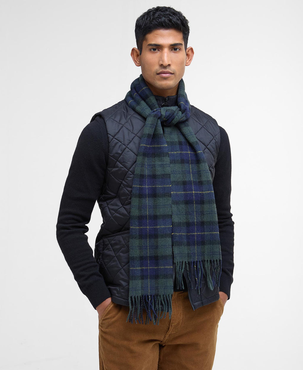 Tartan lambswool scarf in dark plaid with fringed ends, worn around the neck