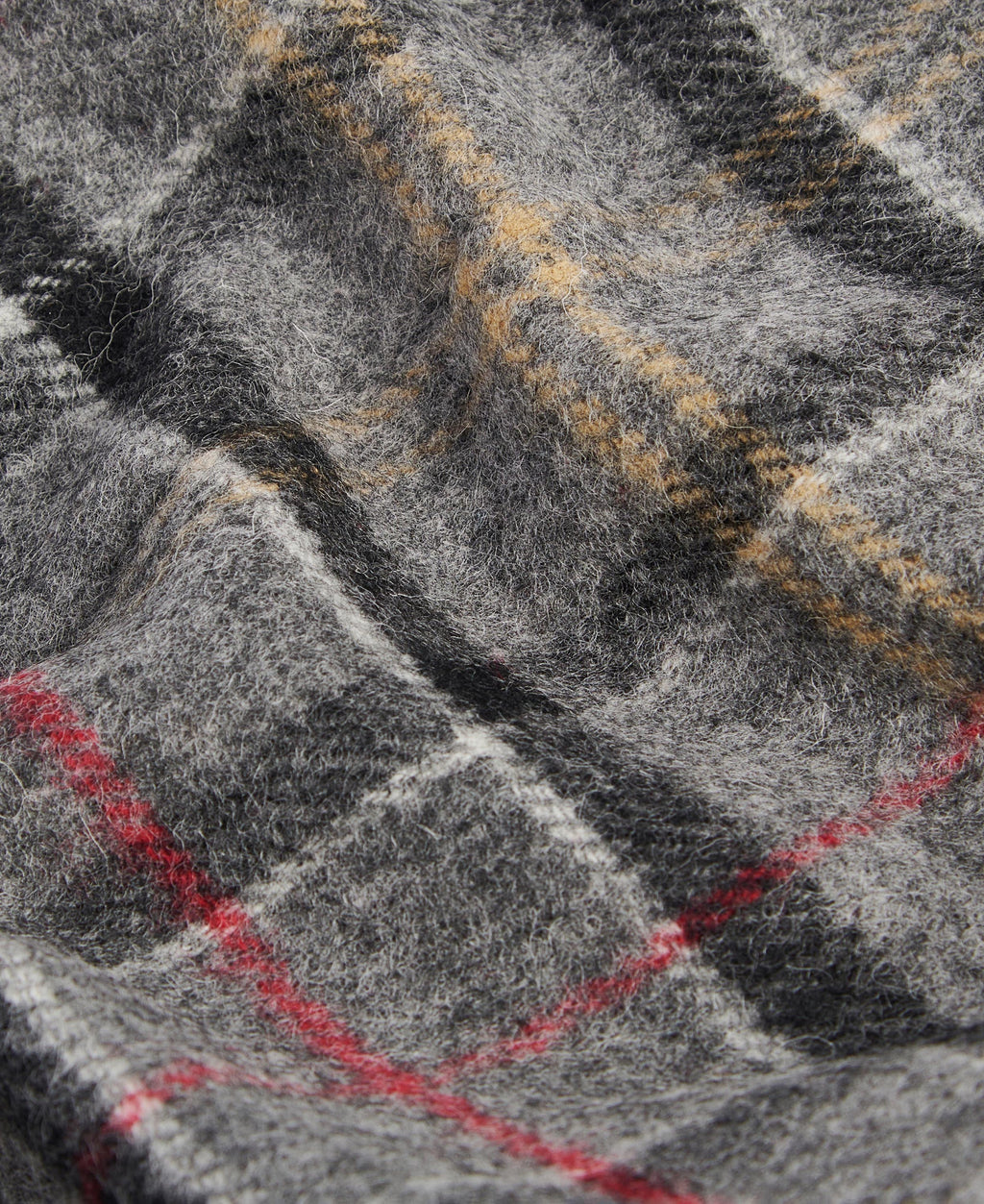 Close-up of grey tartan lambswool fabric with red, yellow, and black grid lines