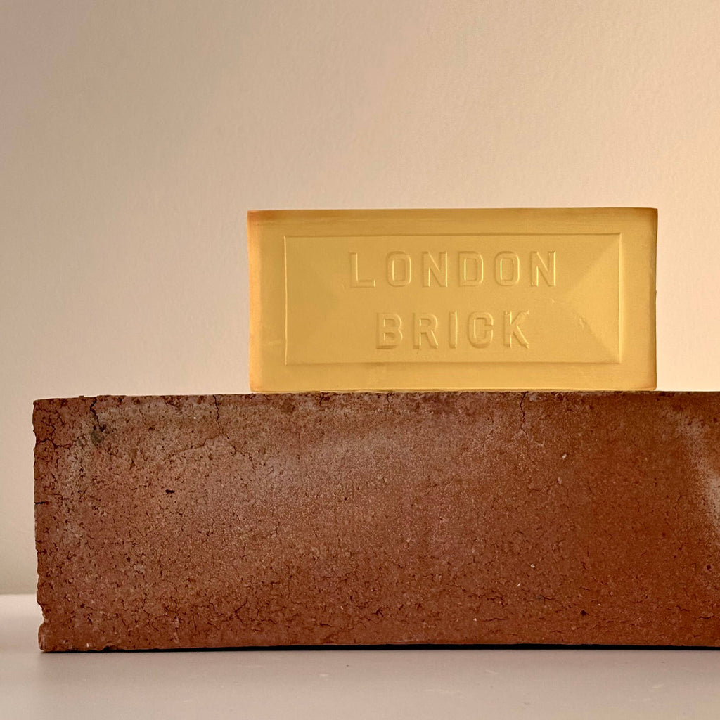 Rectangular brown soap bar with embossed 'LONDON BRICK', with a yellow bar behind.