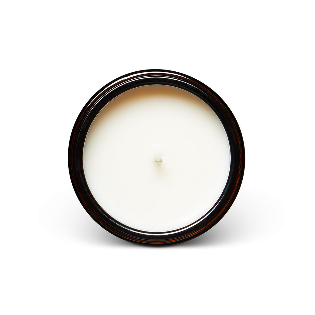 Soy wax candle top with white wax pool and wick inside a dark glass jar