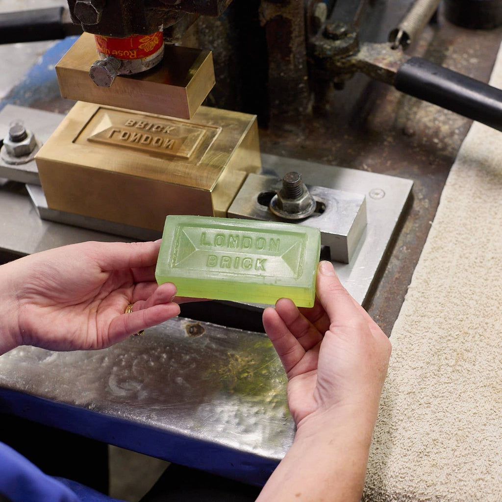 Green soap bar held in hands, embossed 'LONDON BRICK' lettering visible.