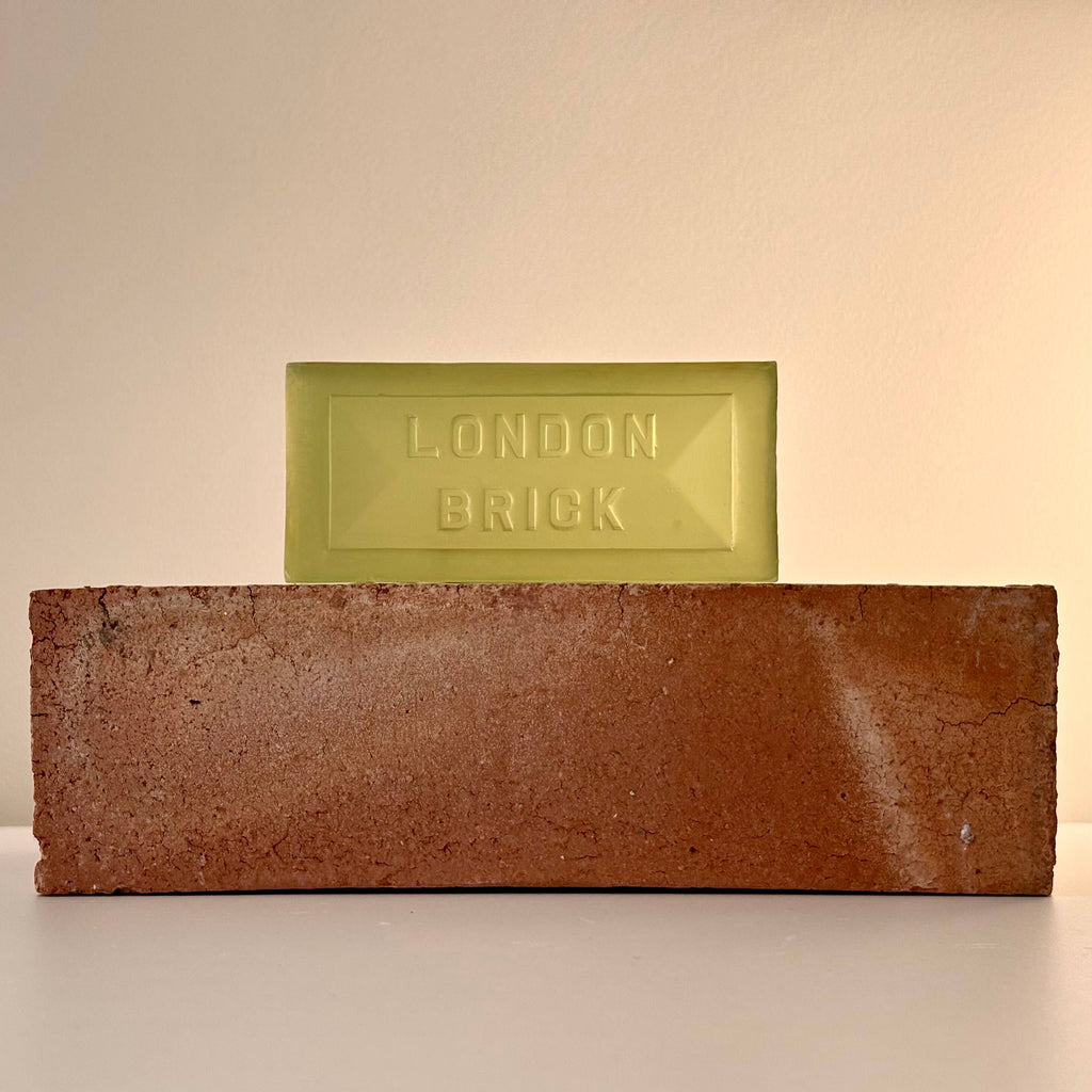 Brown brick-shaped soap bar with embossed 'LONDON BRICK', plus pale green bar behind.