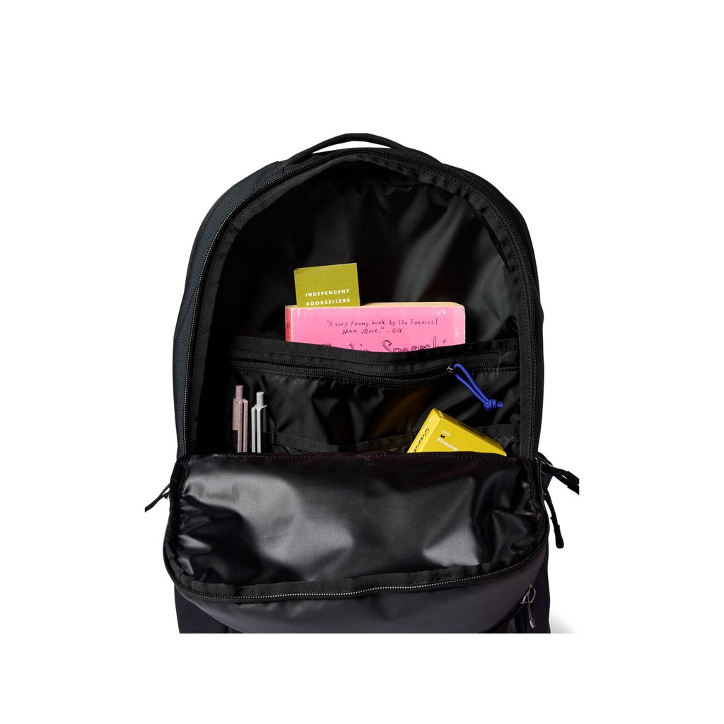 Black daypack interior view with open main compartment and accessory pockets, tags visible