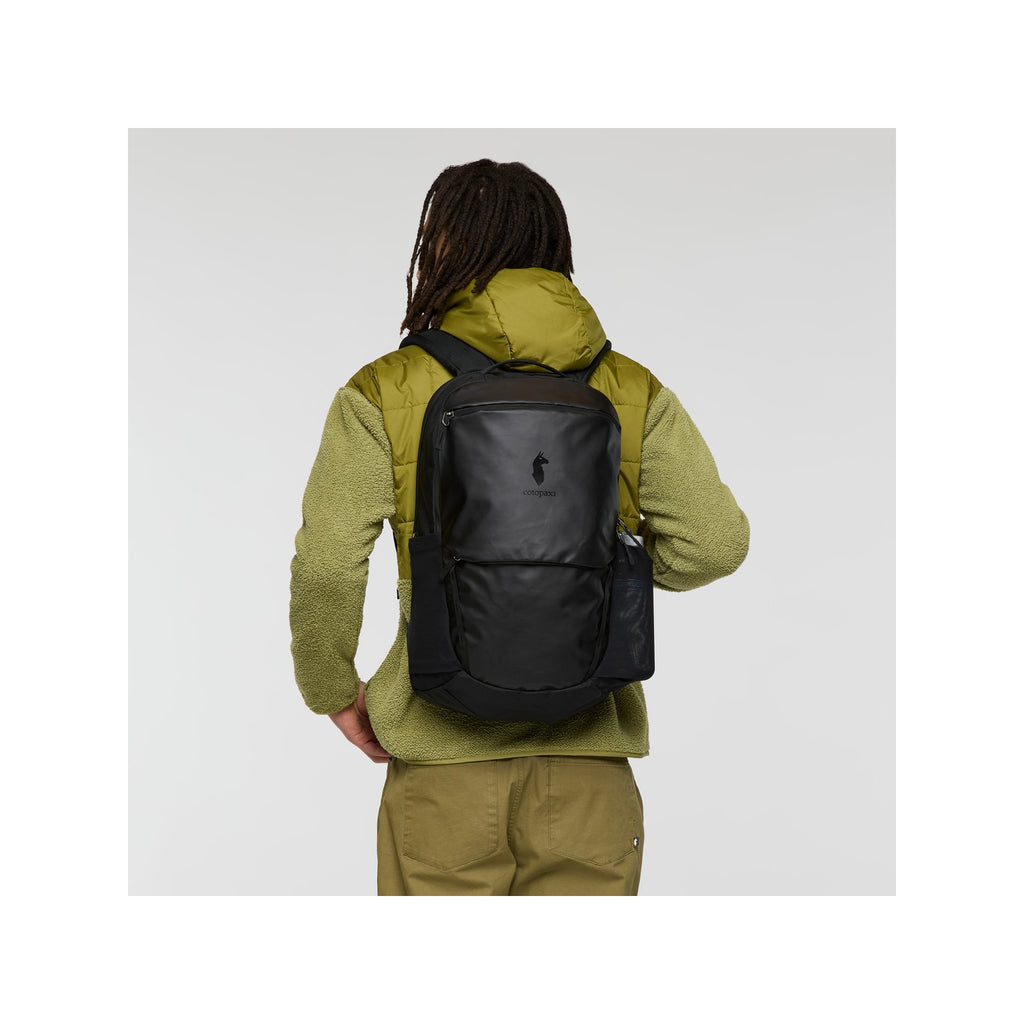 Black Cotopaxi Allpa 26L daypack worn on a person, with shoulder straps and back panel