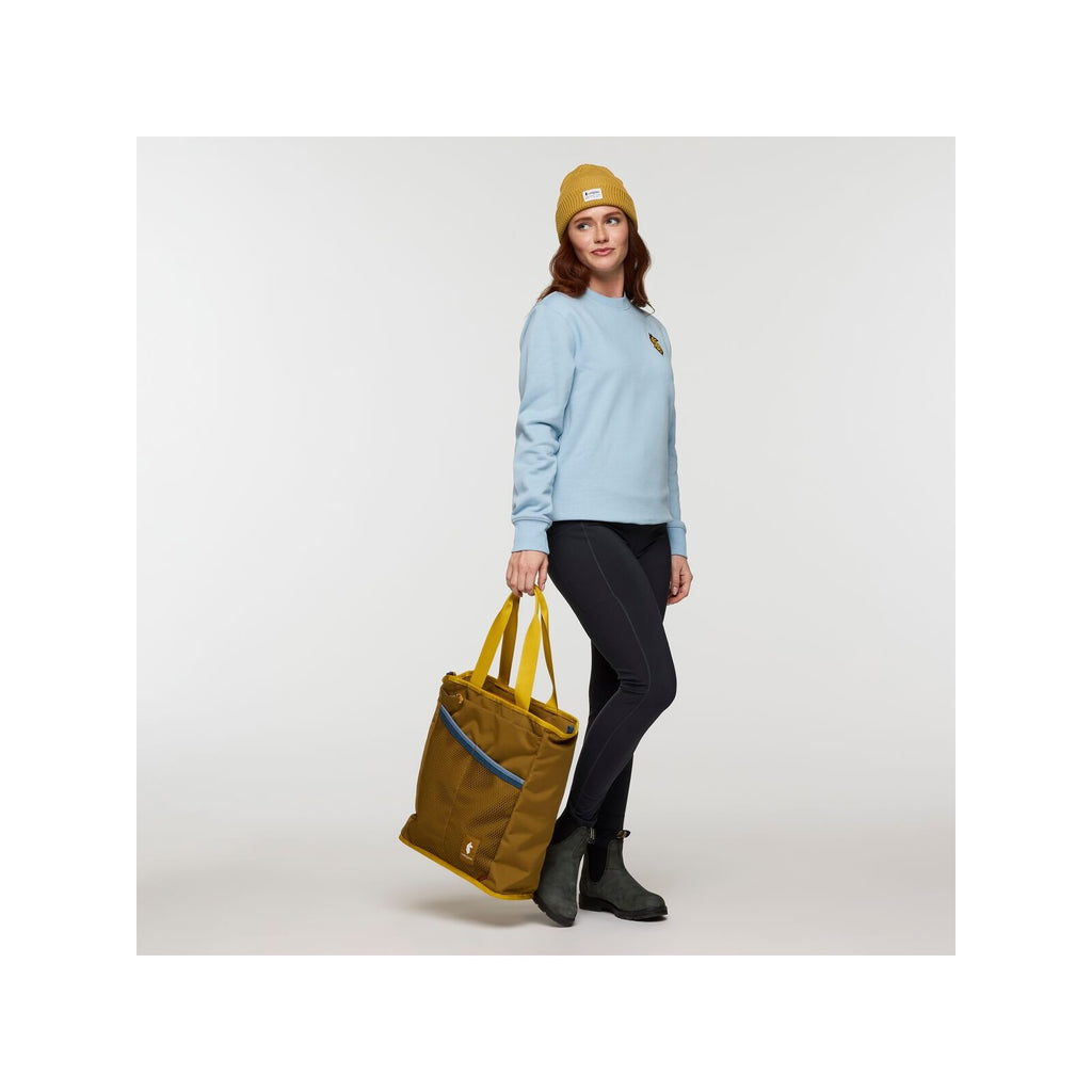 Cotopaxi Todo 22L Convertible Tote in Bronze carried as a tote, showing scale