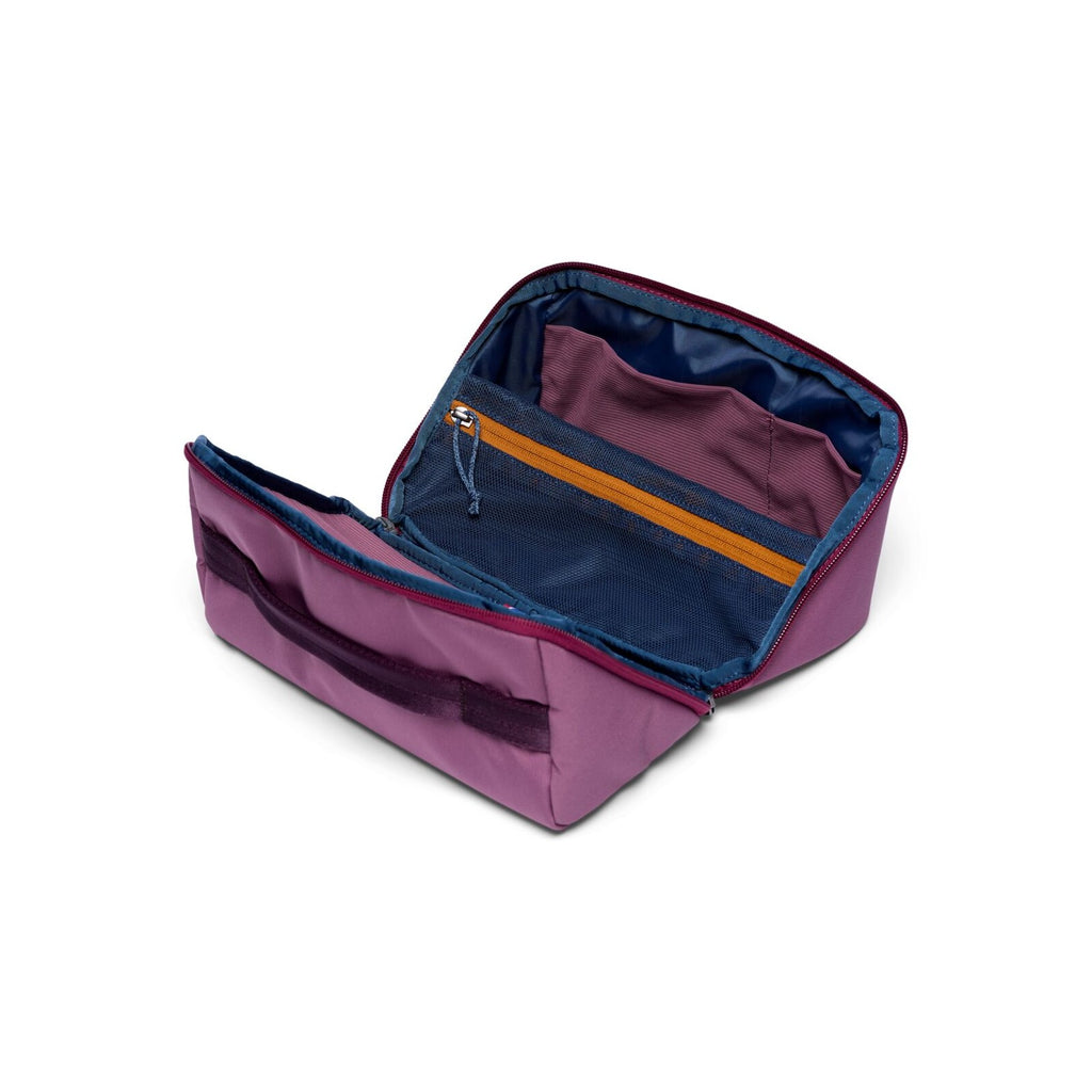 Cotopaxi Viaje Toiletry Kit in Fig, opened flat showing navy lining, mesh pockets and elastic loops