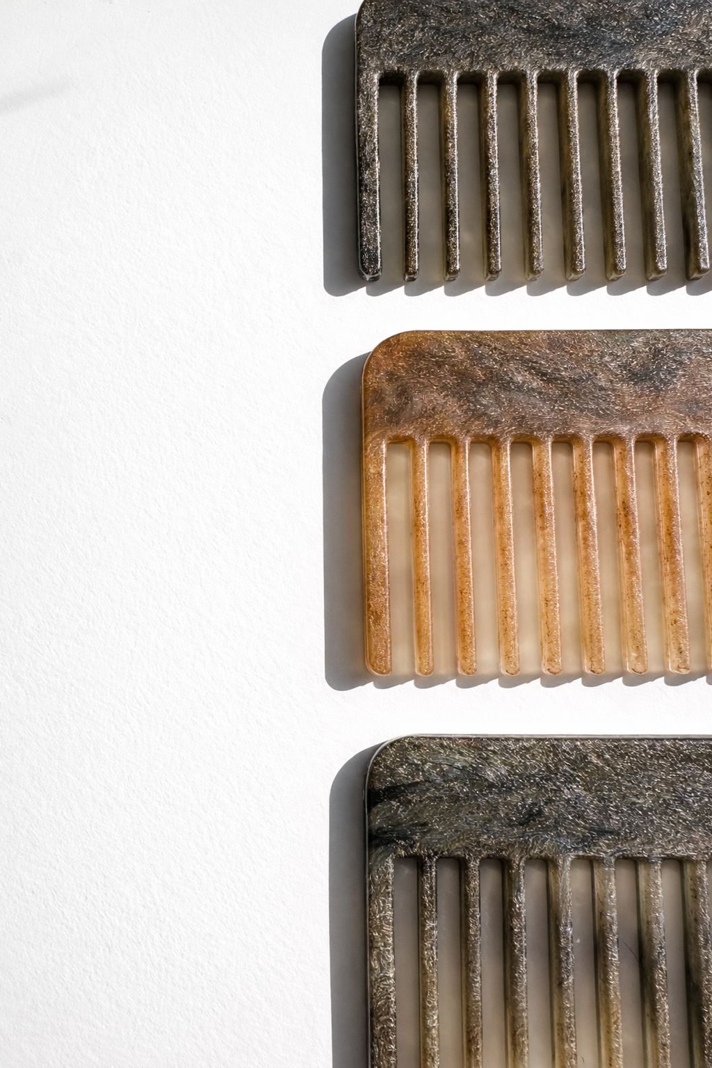Recycled plastic hair combs, close-up of fine teeth in dark and tan.