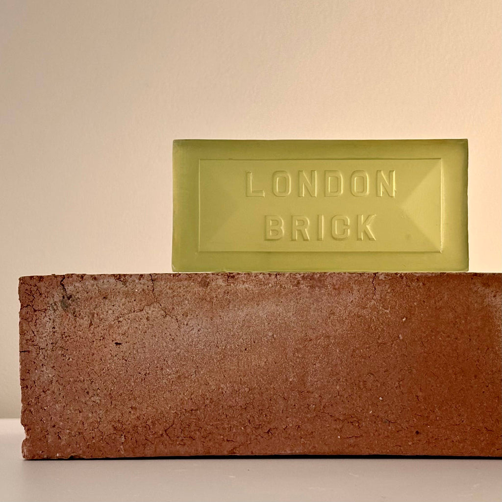 Brown brick-shaped soap bar with a pale green bar behind, both embossed 'LONDON BRICK'.