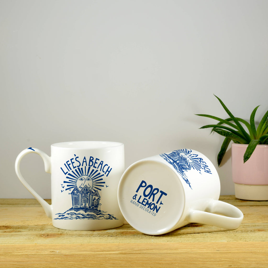 Bone china mug with white body and blue “Life’s a Beach” lighthouse graphic