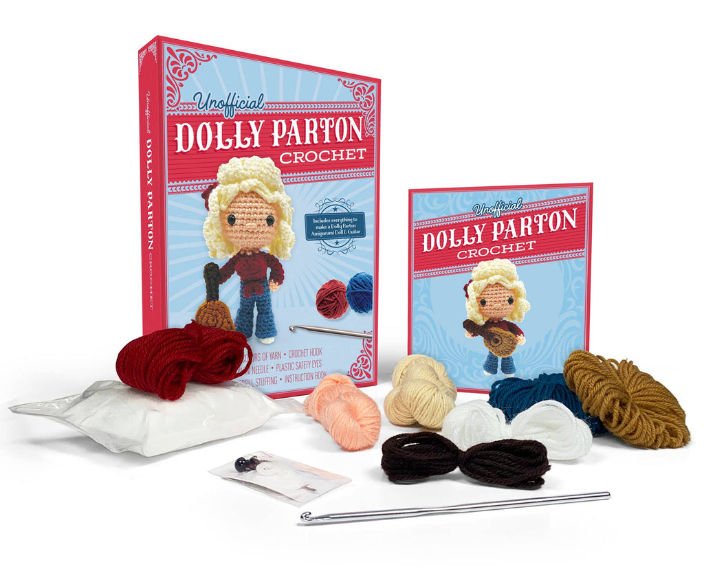 Crochet kit components with book, crocheted doll, yarn skeins, crochet hook, and needle