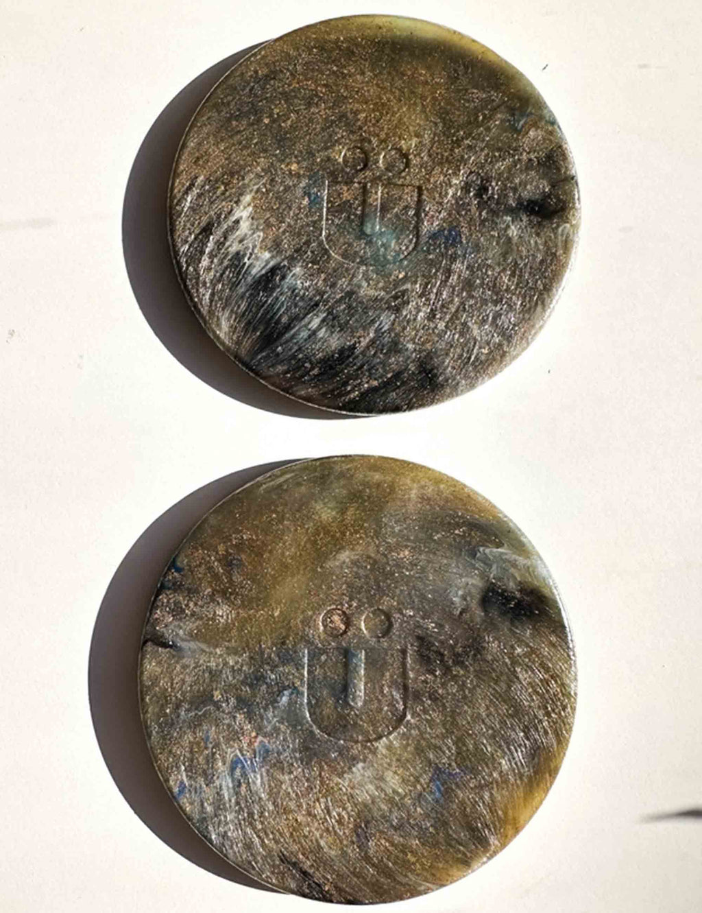 Two round, metallic objects with engraved symbols on a white background