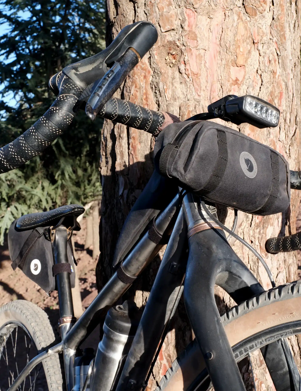 Clay handlebar pocket on a bike with circular logo and webbing mounting straps