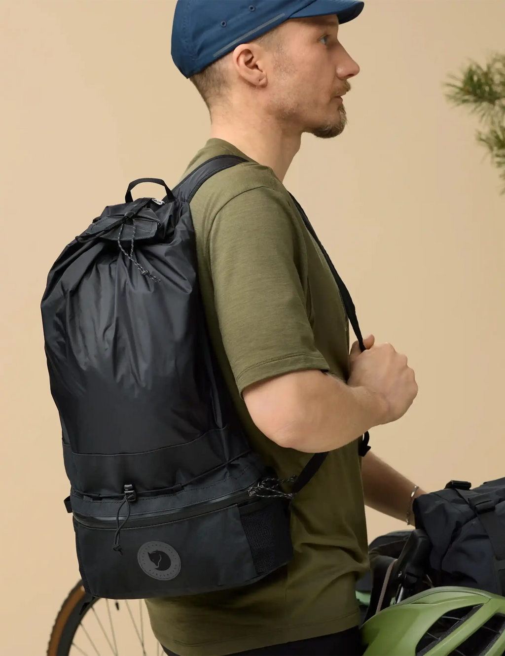 Expandable hip pack worn on back in dark color, with adjustable straps and logo patch.