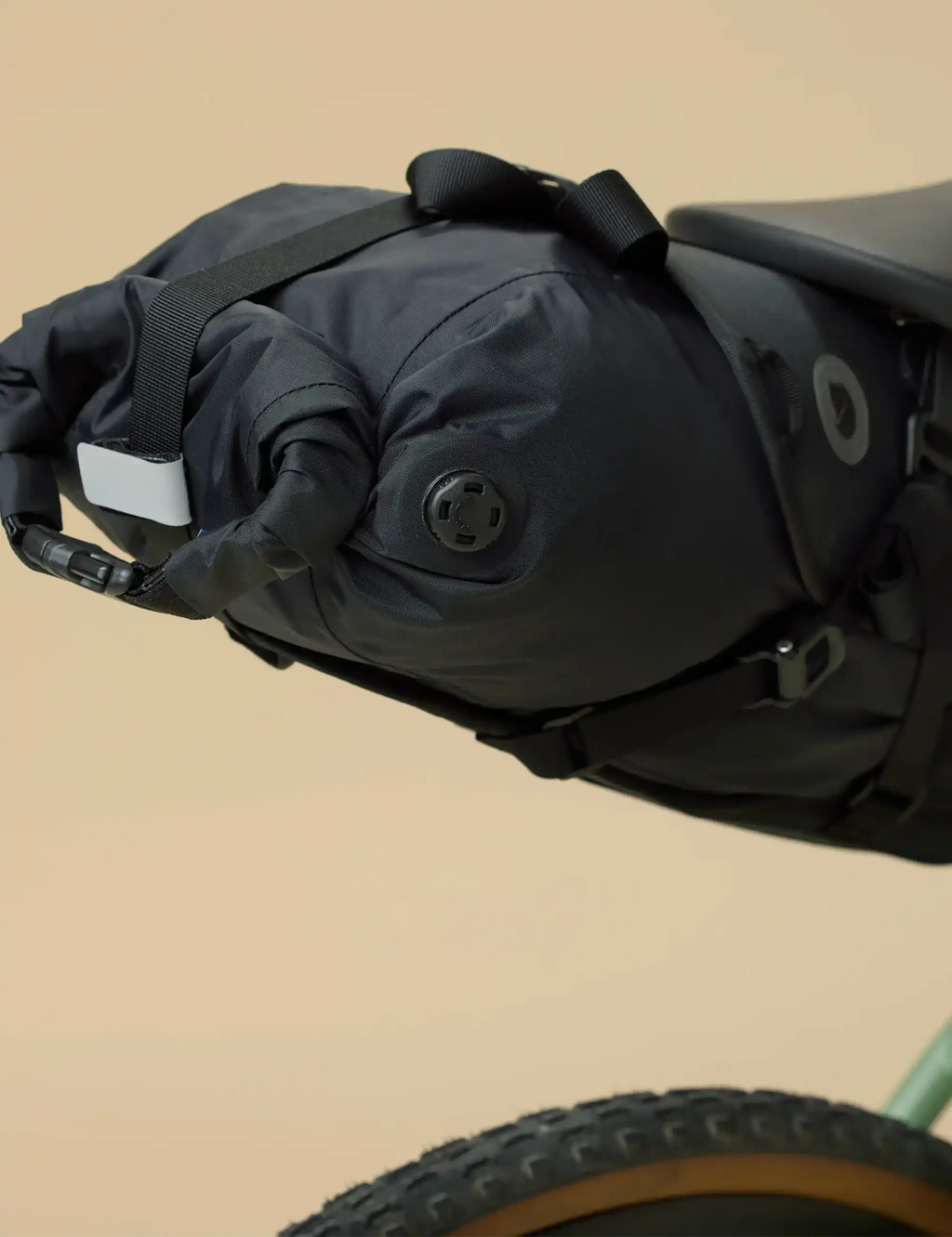 Black roll-top seat dry bag with attachment loop and circular logo patch
