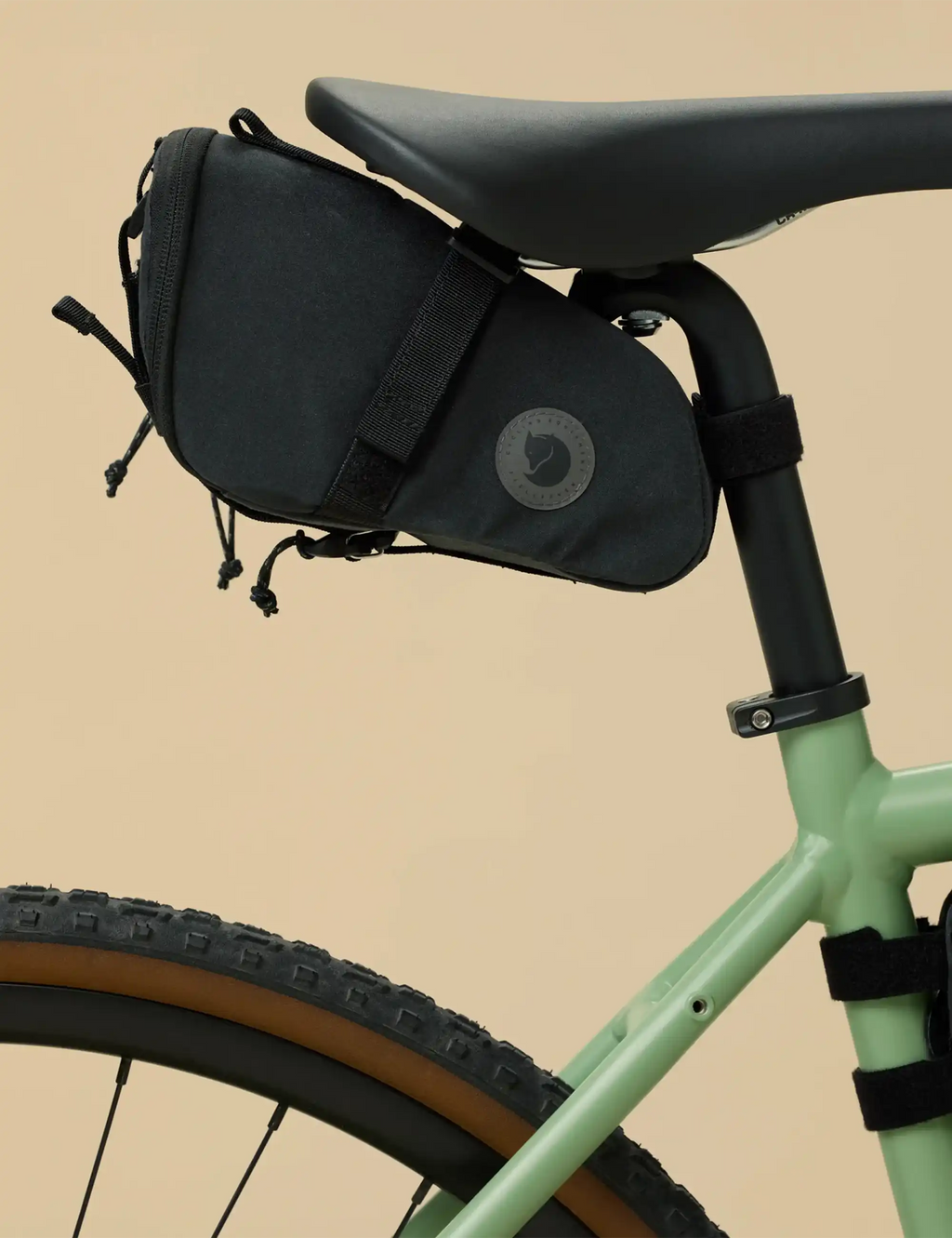 Black bike seat bag with logo patch and elastic cords, mounted on frame