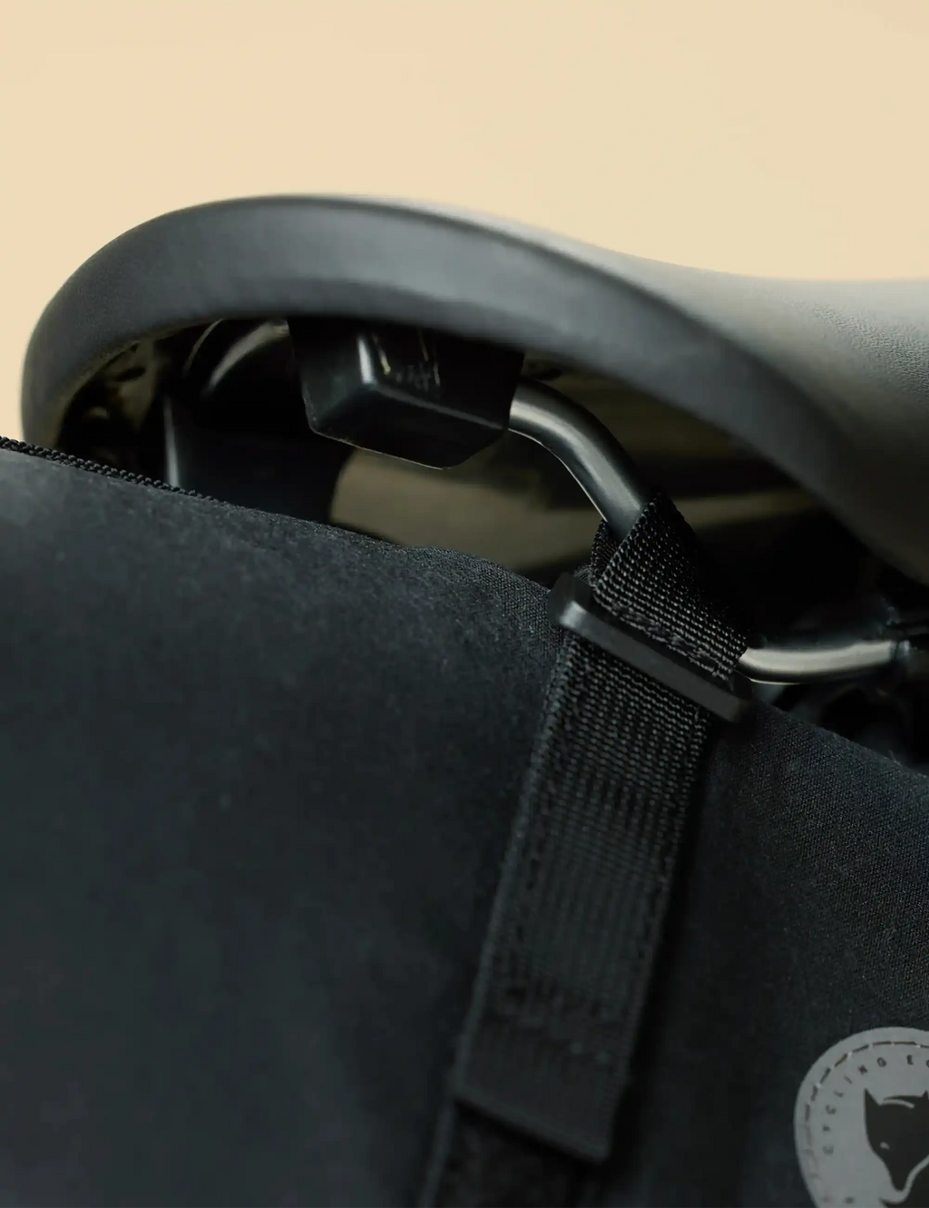 Close-up of black bike seat bag with webbing strap and round logo patch