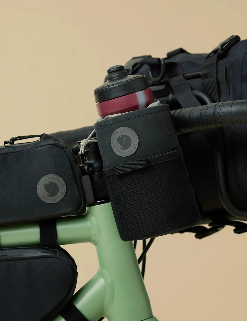 Black bike snack bag with circular logo patch and webbing, mounted on handlebars