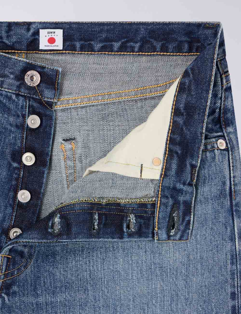 Dark blue denim jeans close-up, front pocket, metal button closure, belt loops