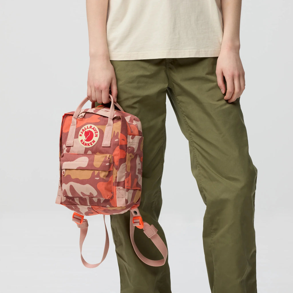 Camouflage mini backpack with orange-pink tones, side handle and front zip pocket