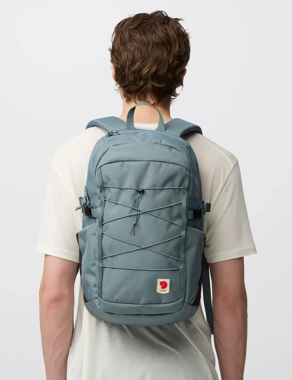 Nimbus blue backpack worn on person, front compartment with lace-style cords and logo patch