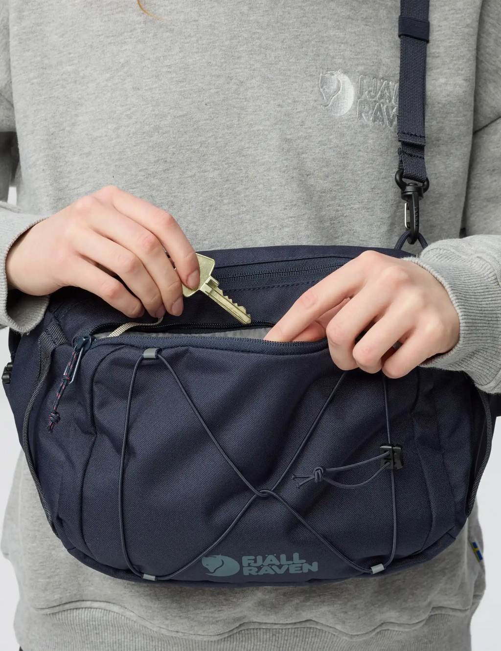 Navy sling bag close-up showing open zipper and inner pocket