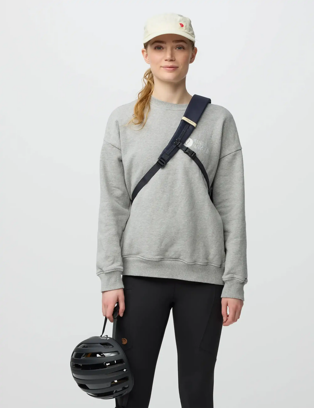 Navy sling bag worn crossbody with front zip pocket and webbing strap